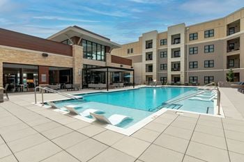 A swimming pool with lounge chairs and a building in the background